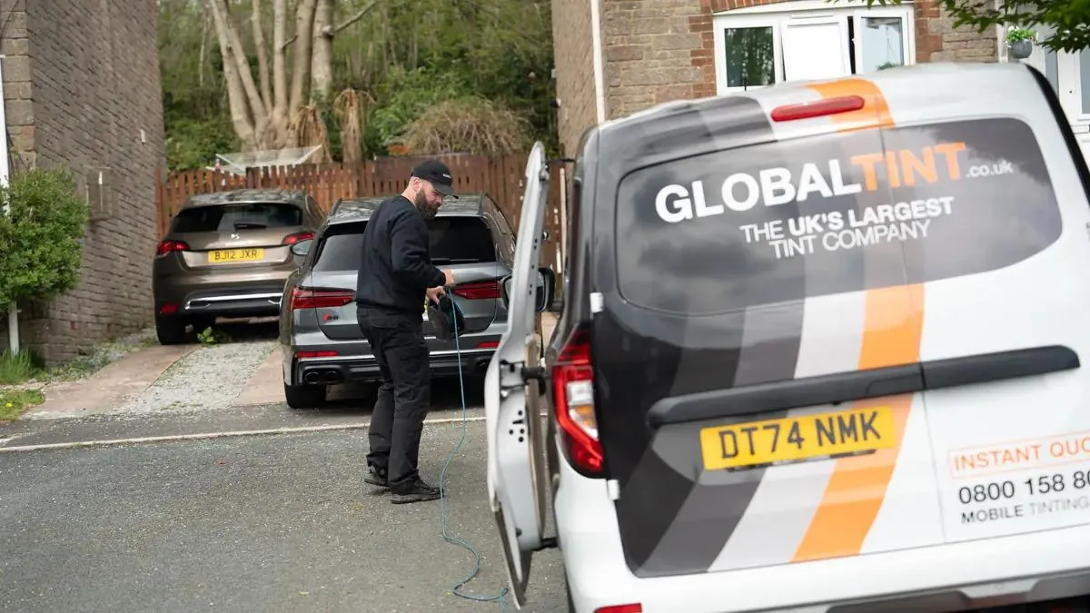 A Global Tint installer setting up on a customer's driveway beside his van