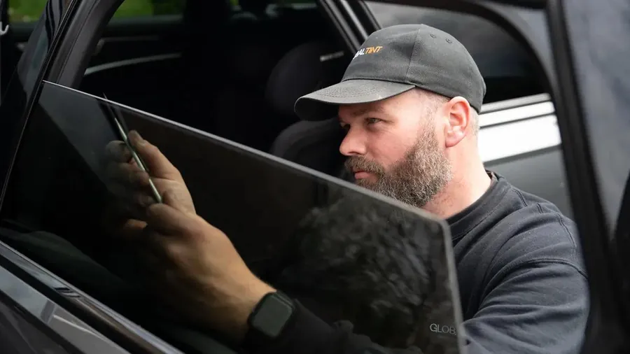Global Tint installer fitting film to a car side window