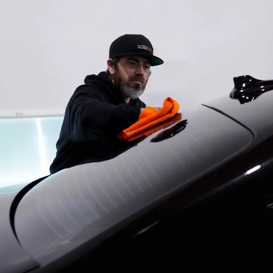 Global Tint installer finishing a freshly tinted car window