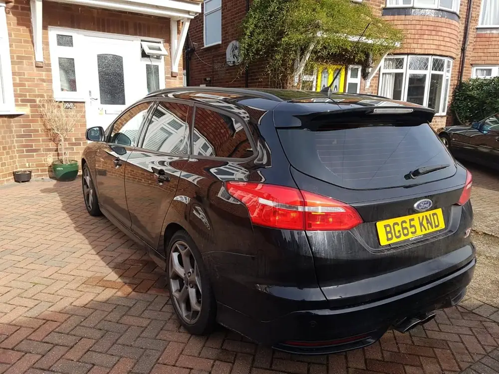 Black estate with dark rear side windows and rear windscreen, parked on a brick driveway.