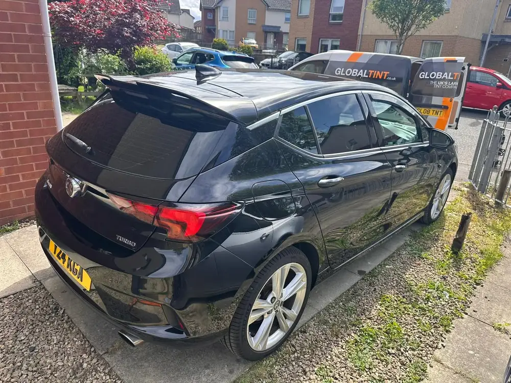 Black Vauxhall Astra Turbo with dark rear side windows and back windscreen, viewed from behind on a driveway