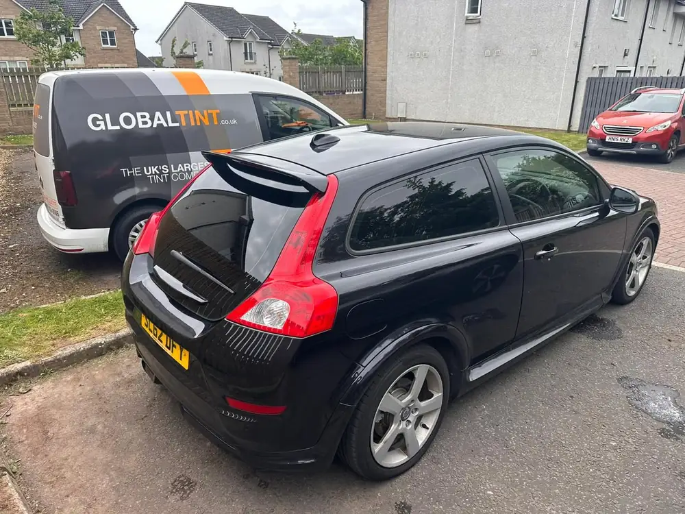 Black Volvo C30 with dark rear side windows and rear windscreen, seen from the rear quarter.