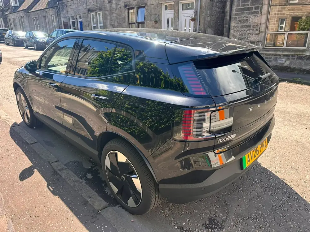 Black Volvo EX30 with tinted rear side windows and rear windscreen, parked beside a kerb