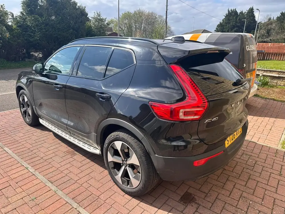 Black Volvo XC40 with dark rear side windows and rear windscreen, parked on a brick driveway.