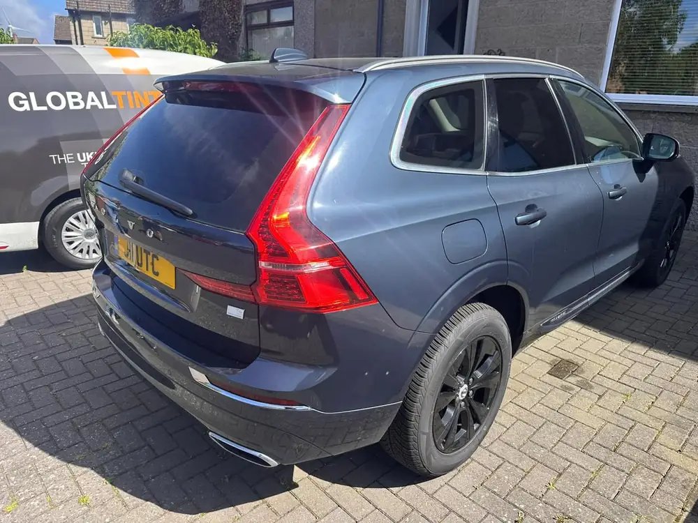 Blue-grey Volvo XC90 viewed from the rear side, with dark rear side windows and rear windscreen