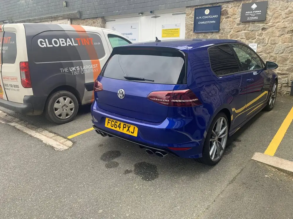 Blue hatchback seen from the rear quarter, with dark tint on the rear windscreen and visible rear side window.