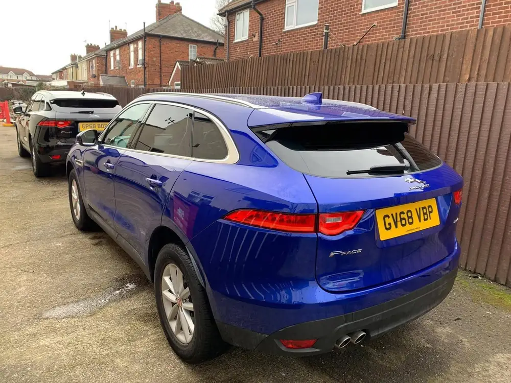 Blue Jaguar F-PACE with dark rear side windows and rear windscreen, viewed from the rear.