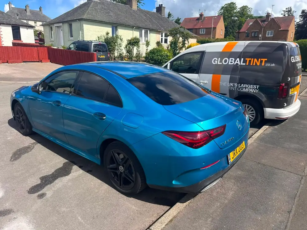 Blue Mercedes-Benz CLA with dark rear side glass and back windscreen, parked beside a Global Tint van