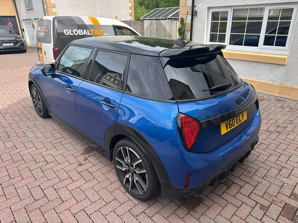 Blue MINI Cooper with a black roof and dark rear windows and back windscreen, parked on a brick driveway
