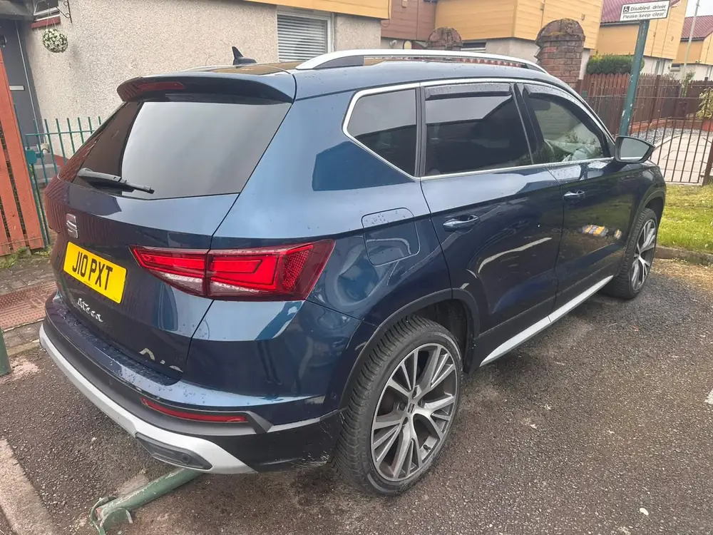 Blue SEAT Ateca with dark rear side windows and rear windscreen, viewed from behind