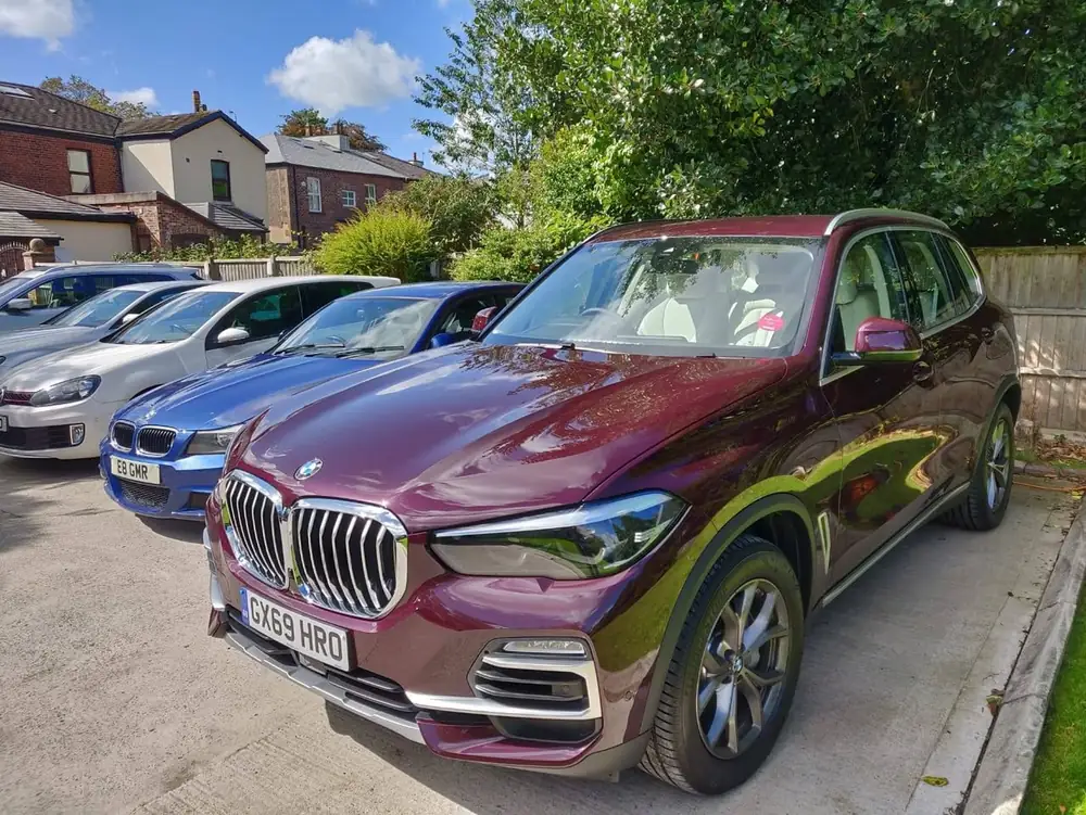 Burgundy SUV with rear side glass that appears darker than the front, parked beside other cars.