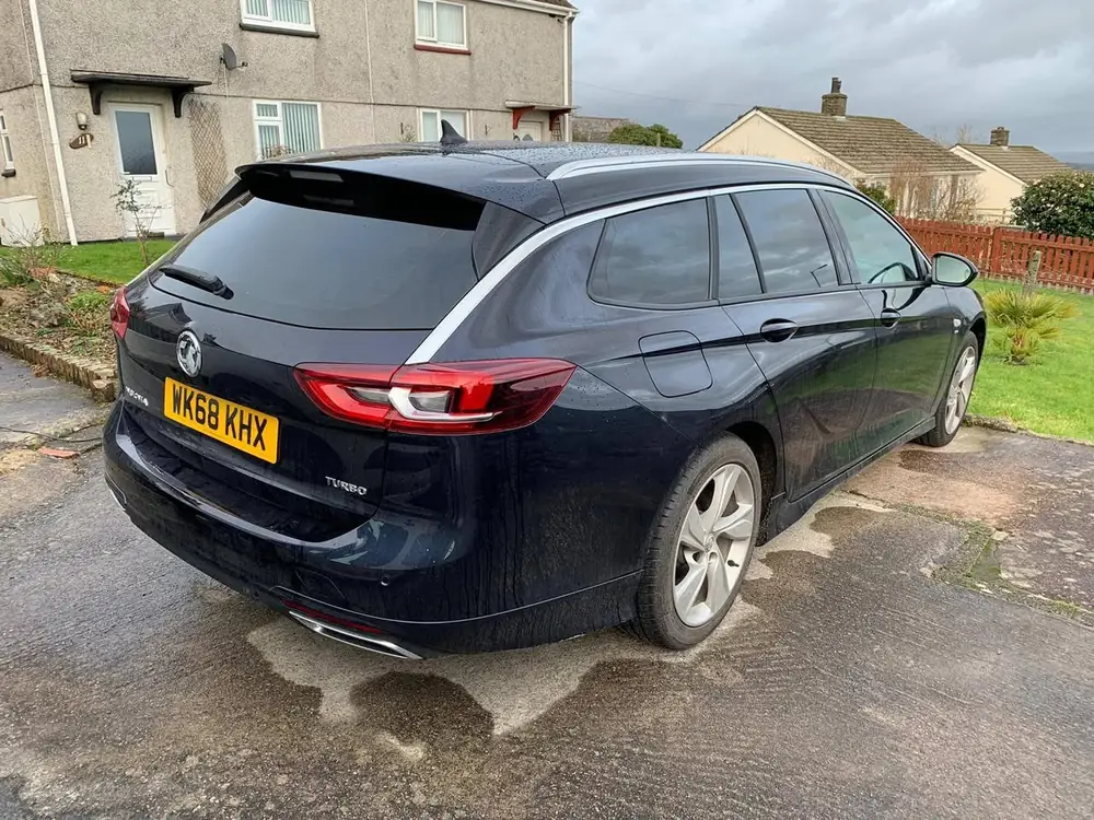 Dark blue estate with visible rear side windows and rear windscreen tinted dark, parked on a driveway