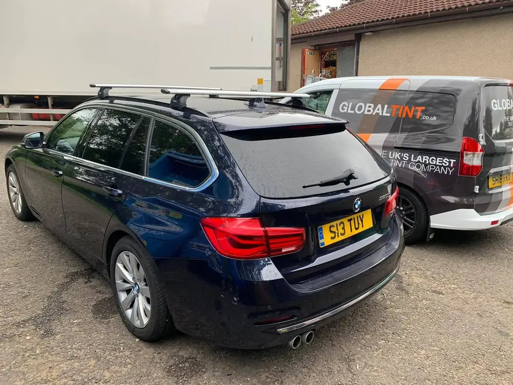 Dark blue estate with roof bars and dark tinted rear side windows and back windscreen.