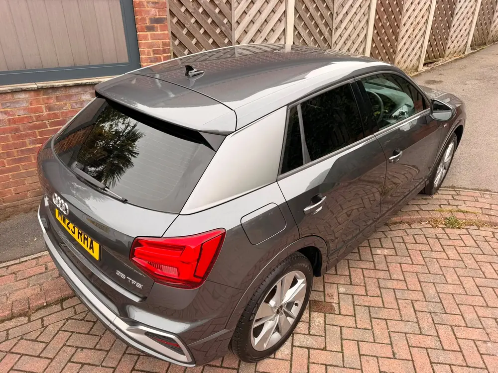 Dark grey Audi Q2 with tinted rear windows, parked on block paving