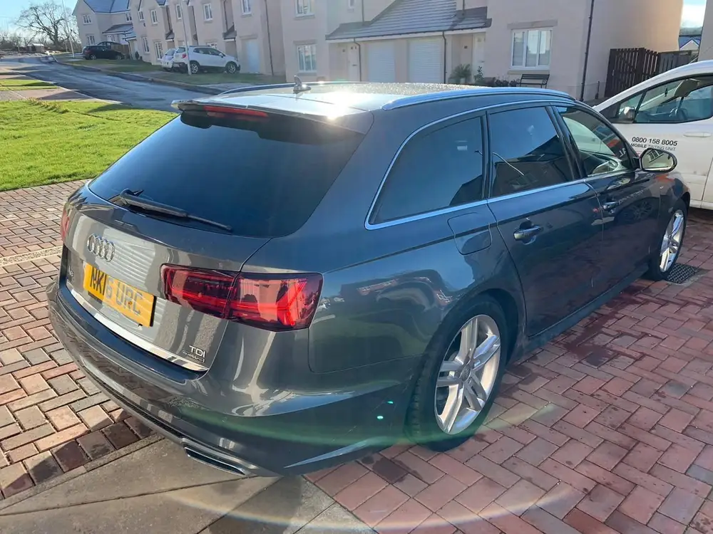 Dark grey estate with dark visible rear side windows and rear windscreen, parked on a paved driveway.