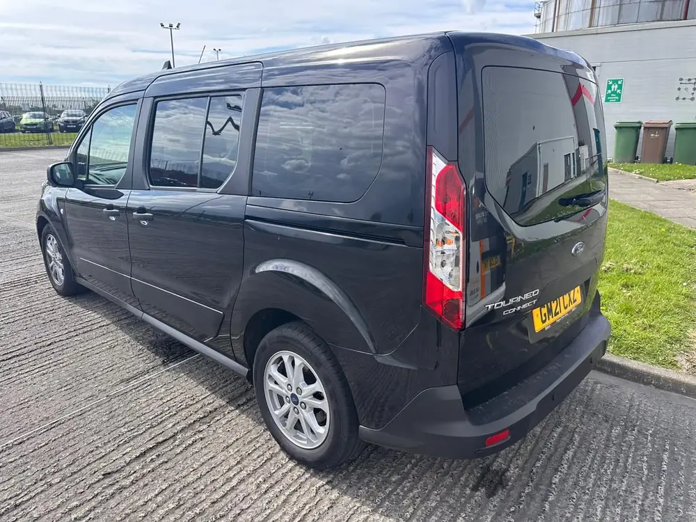 Dark grey Ford Tourneo Connect with dark rear windows and back windscreen, parked on concrete.