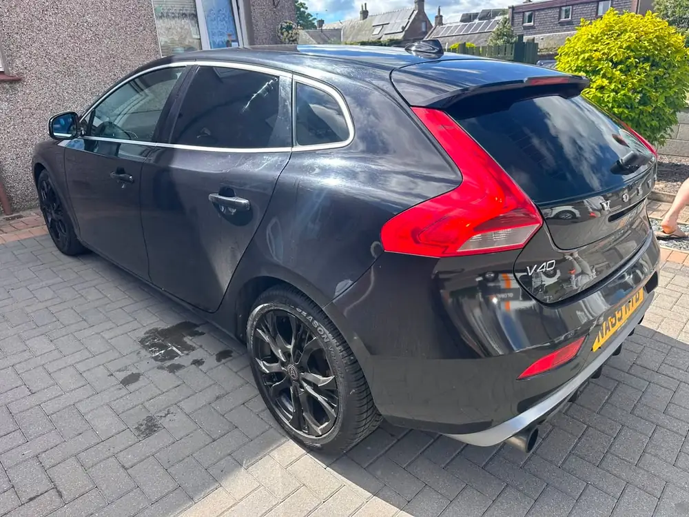 Dark grey Volvo V40 with dark rear side windows and back windscreen, parked on a paved driveway.