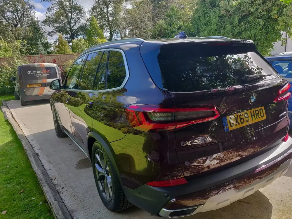 Dark purple BMW X5 with dark rear side windows and rear windscreen, parked on a driveway