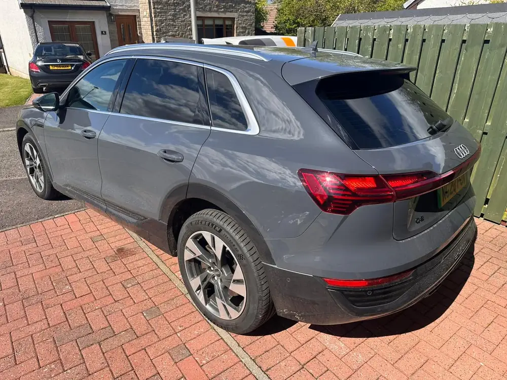 Grey Audi Q8 with dark rear side windows and rear windscreen, parked on a brick driveway