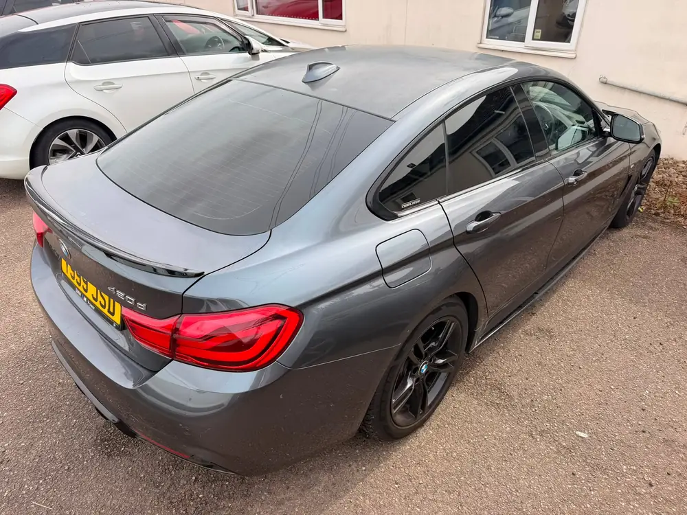 Grey BMW 4 Series Gran Coupé with dark rear side glass and a tinted rear windscreen, parked beside a white car
