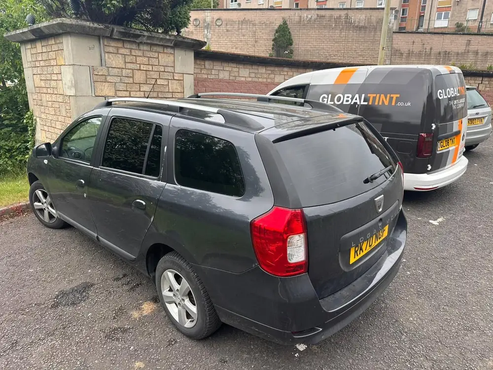 Grey Dacia Logan MCV with dark rear side windows and back windscreen, parked beside a Global Tint van