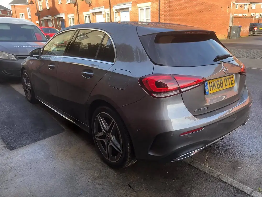 Grey Mercedes-Benz A180d with dark rear windows, parked beside a Global Tint van.