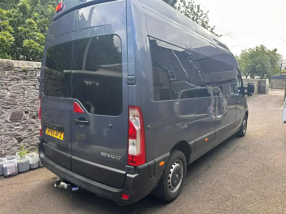 Grey Renault Master campervan with dark rear door glass and side windows, viewed from behind.