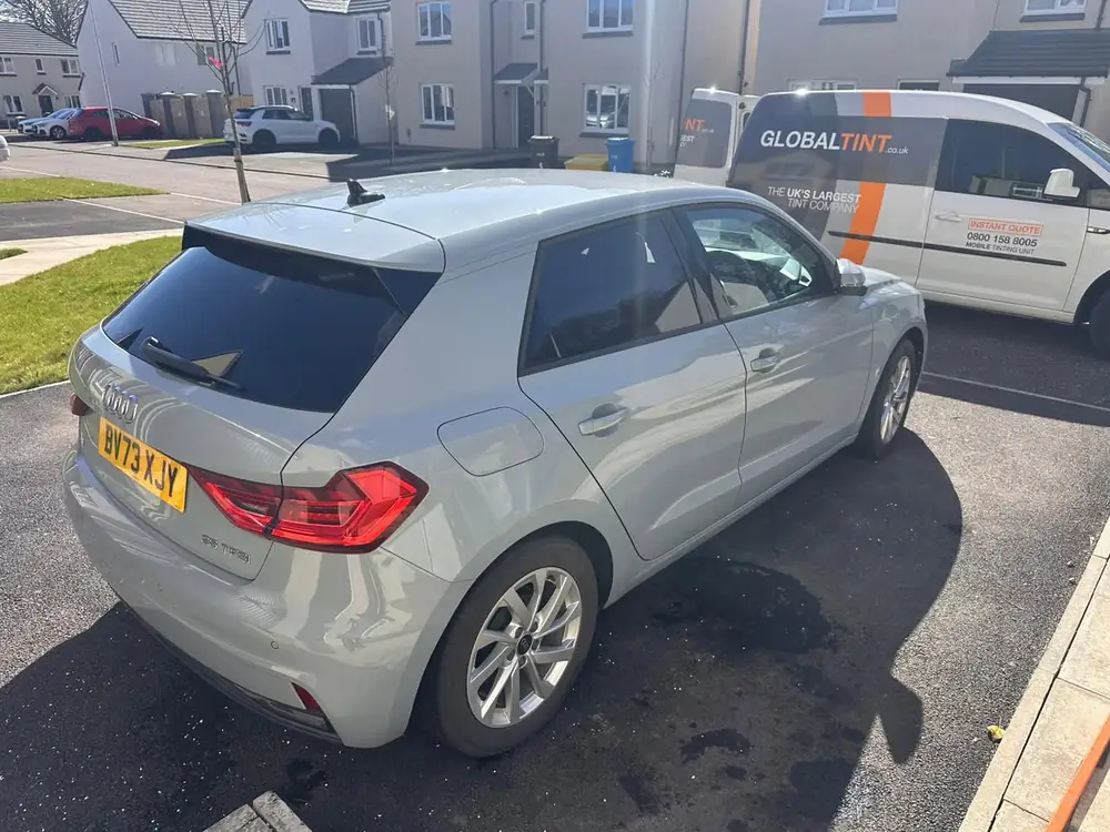 Light grey Audi A1 with a dark rear side window and back windscreen, parked beside a Global Tint van