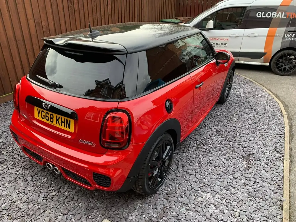 Red MINI Cooper S with a black roof and dark rear side windows and rear windscreen, parked on gravel.