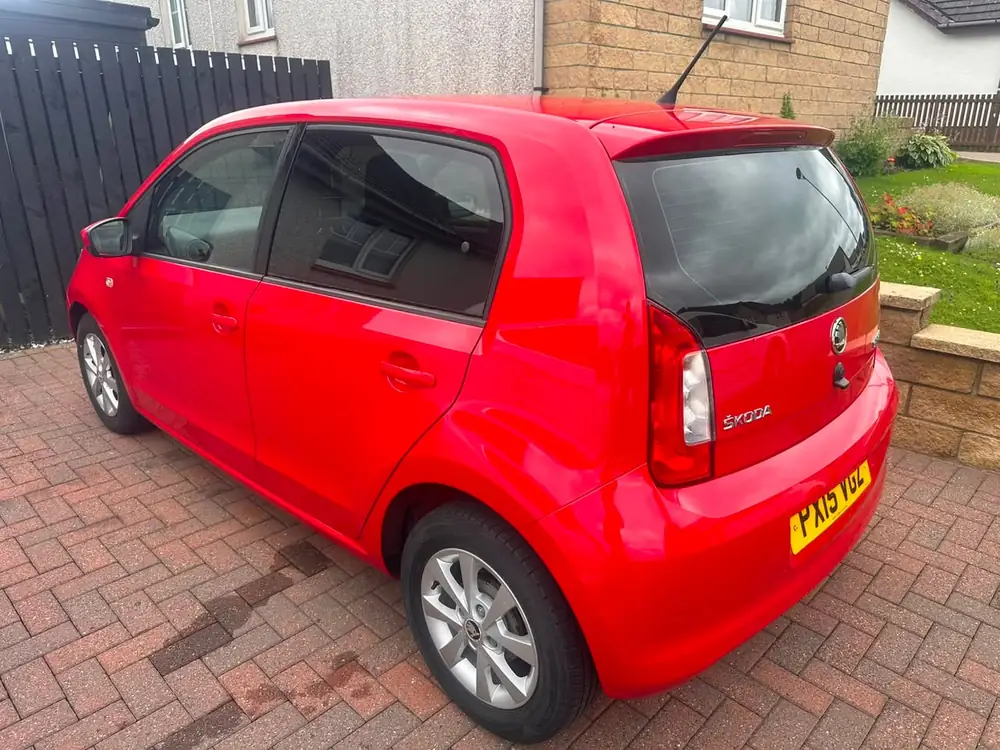 Red Skoda Citigo with a dark rear side window and rear windscreen, parked on a paved driveway.
