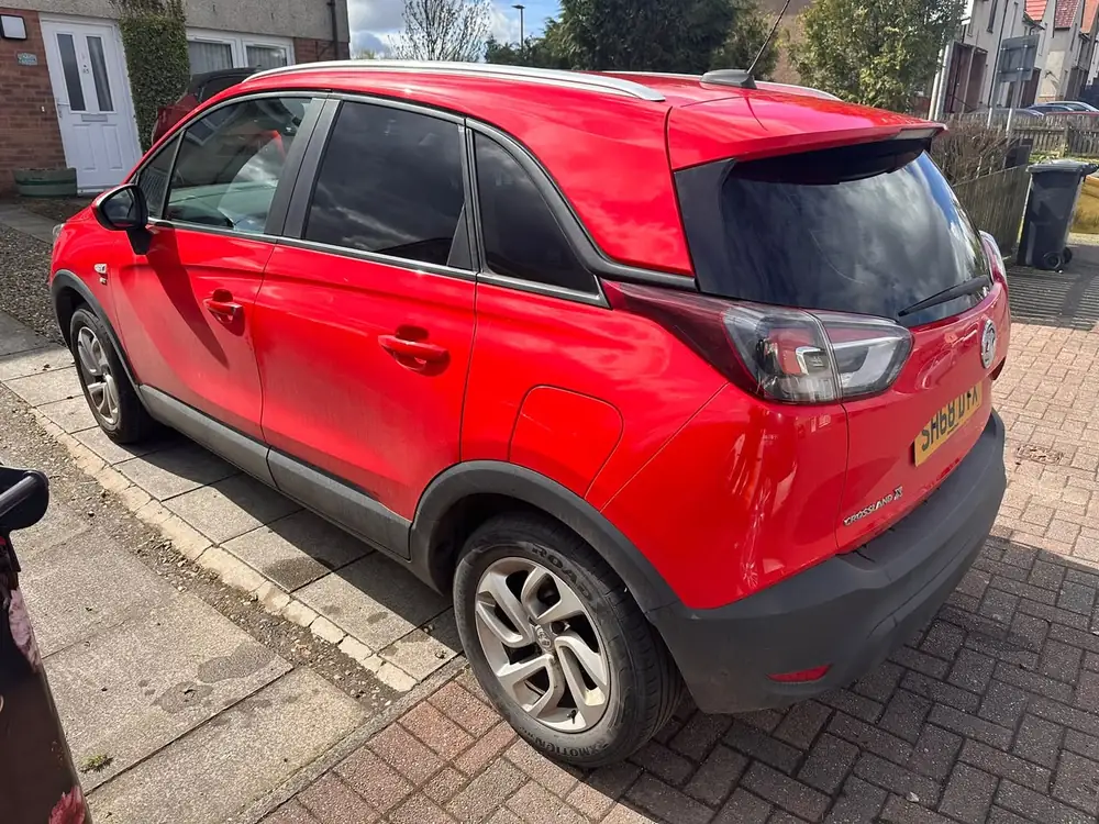 Red Vauxhall Crossland X showing dark rear side glass and rear windscreen, parked on a paved driveway