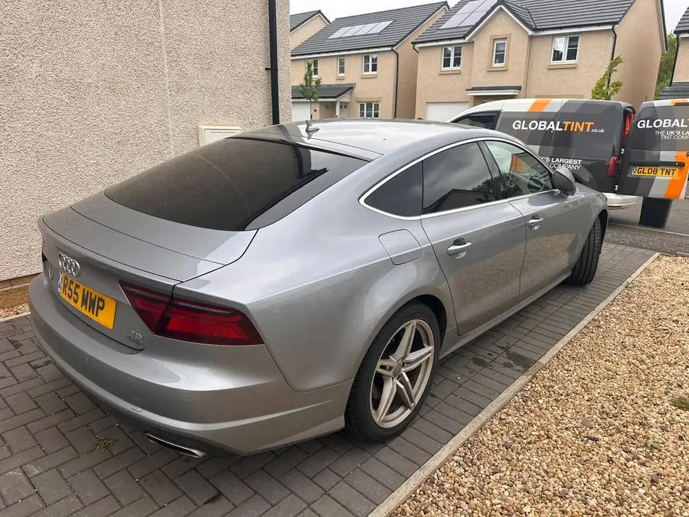 Silver Audi A7 with dark tint on the visible rear side windows and rear windscreen, parked on a paved driveway.