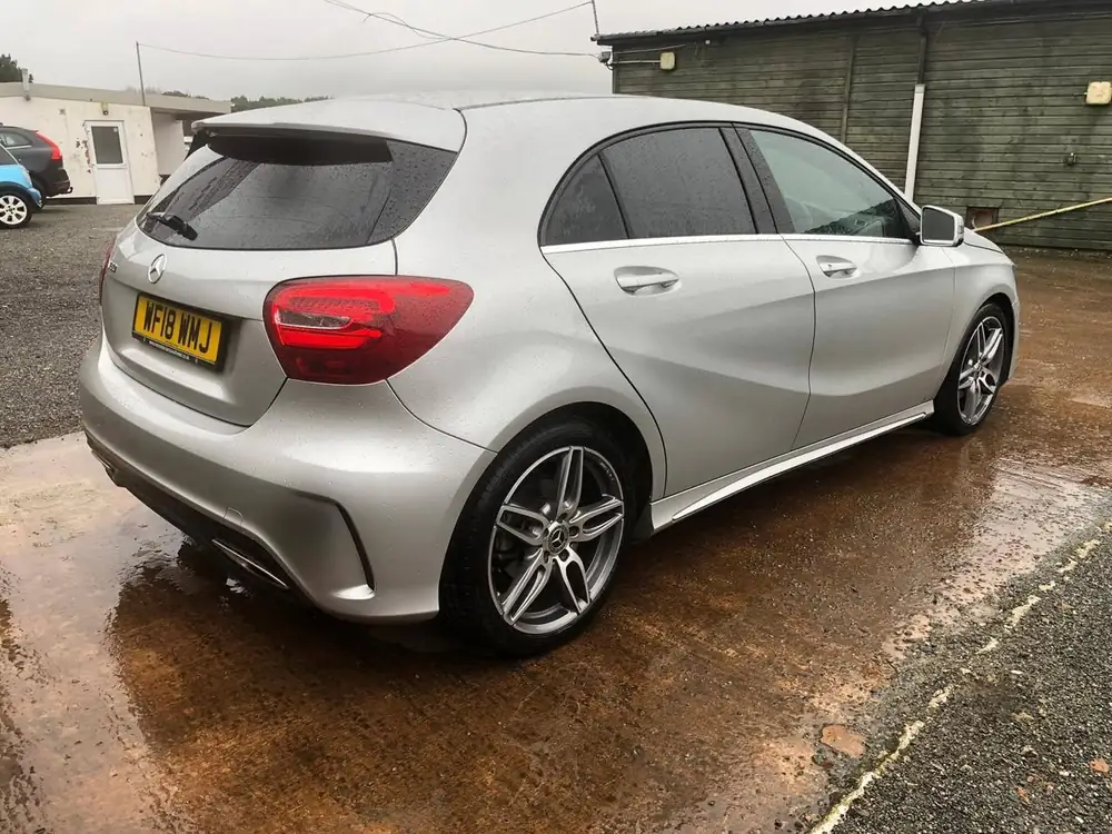 Silver hatchback with dark rear side windows and rear windscreen, parked on wet paving.