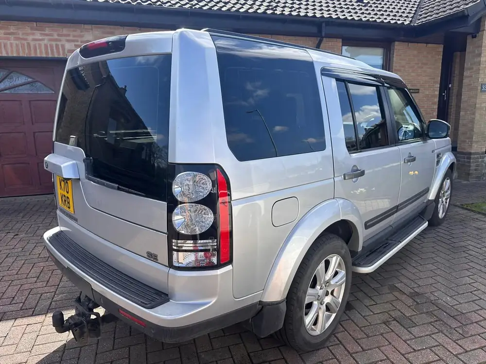 Silver Land Rover Discovery 4 with dark rear side glass and rear windscreen, parked on a block-paved driveway