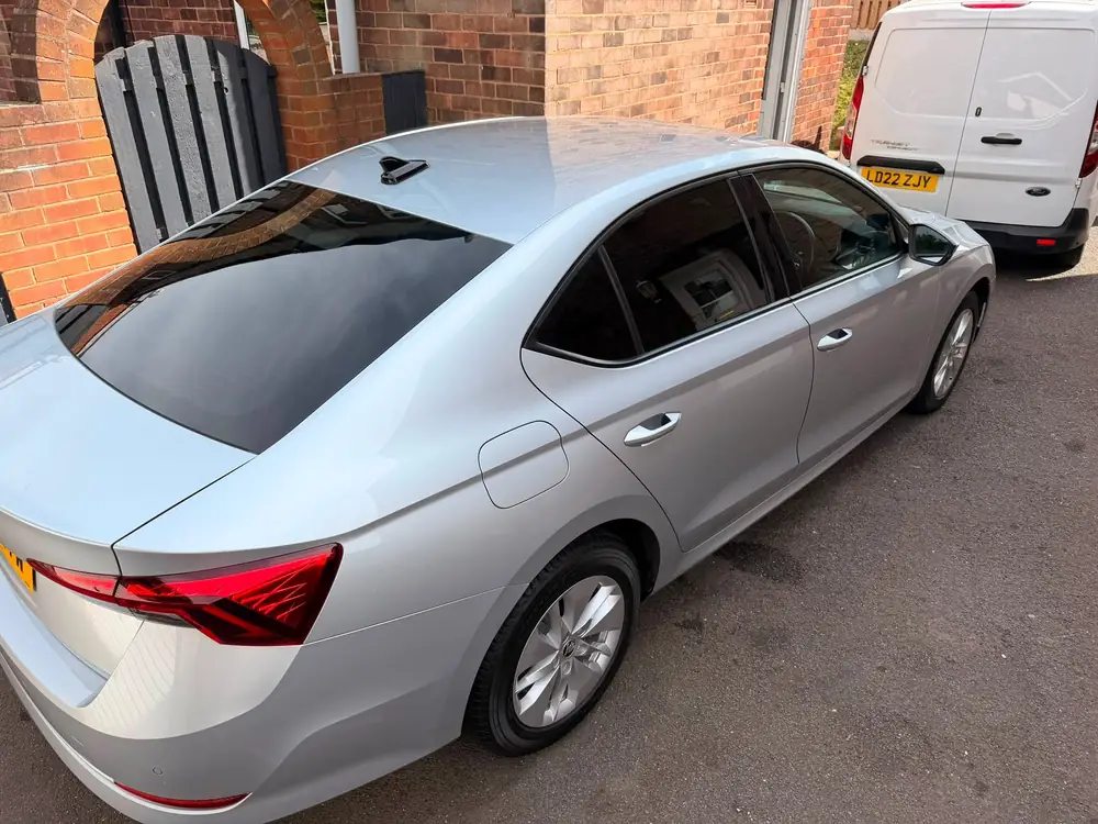 Silver Skoda Superb with dark rear side windows and rear windscreen, parked beside a white van