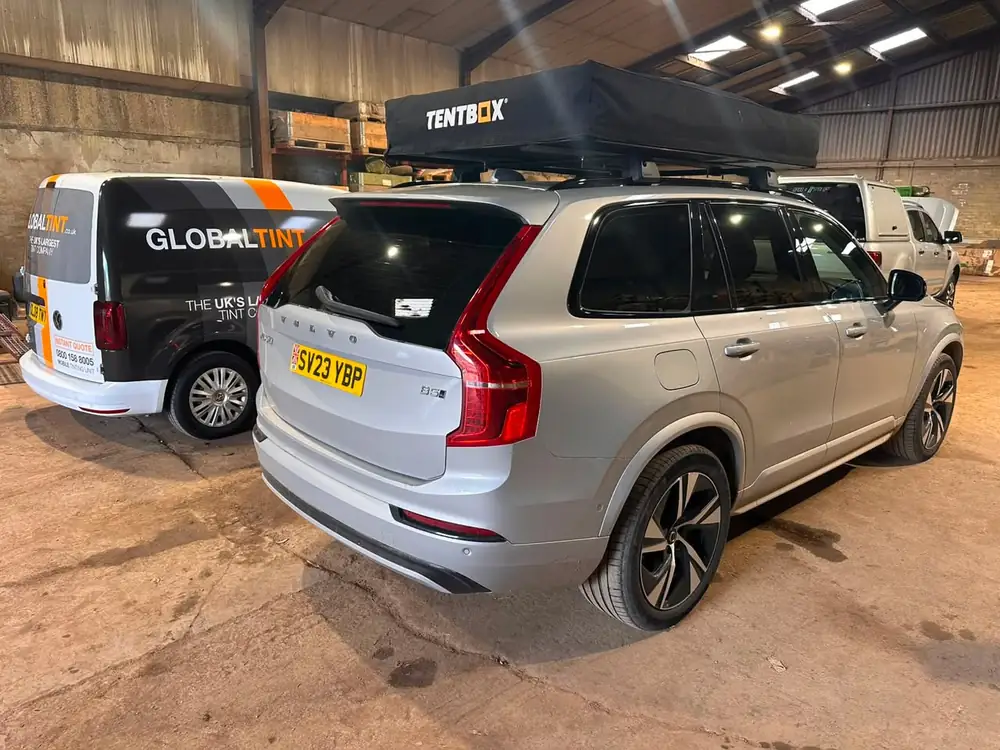 Silver Volvo XC90 with dark rear windows and a roof tent, parked indoors