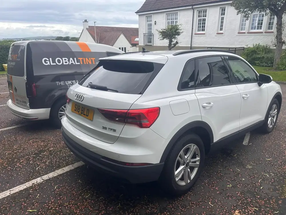 White Audi Q3 with dark rear side windows and rear windscreen, parked beside a Global Tint van.