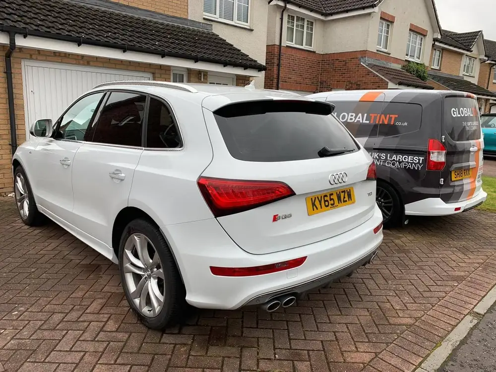 White Audi SQ5 with dark rear side windows and back windscreen, parked beside a Global Tint van
