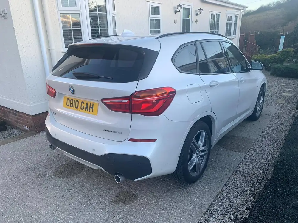 White BMW X1 with dark rear side windows and back windscreen, parked on a driveway.