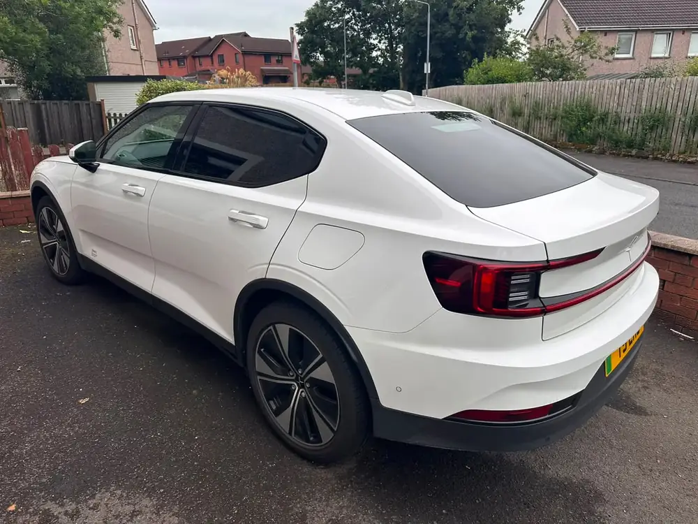 White Polestar 2 with its rear side window and rear windscreen tinted dark, parked on a driveway