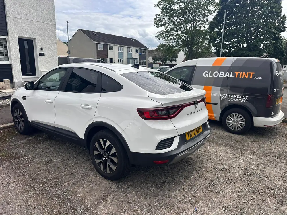 White Renault Arkana with dark rear windows, parked beside a Global Tint van.