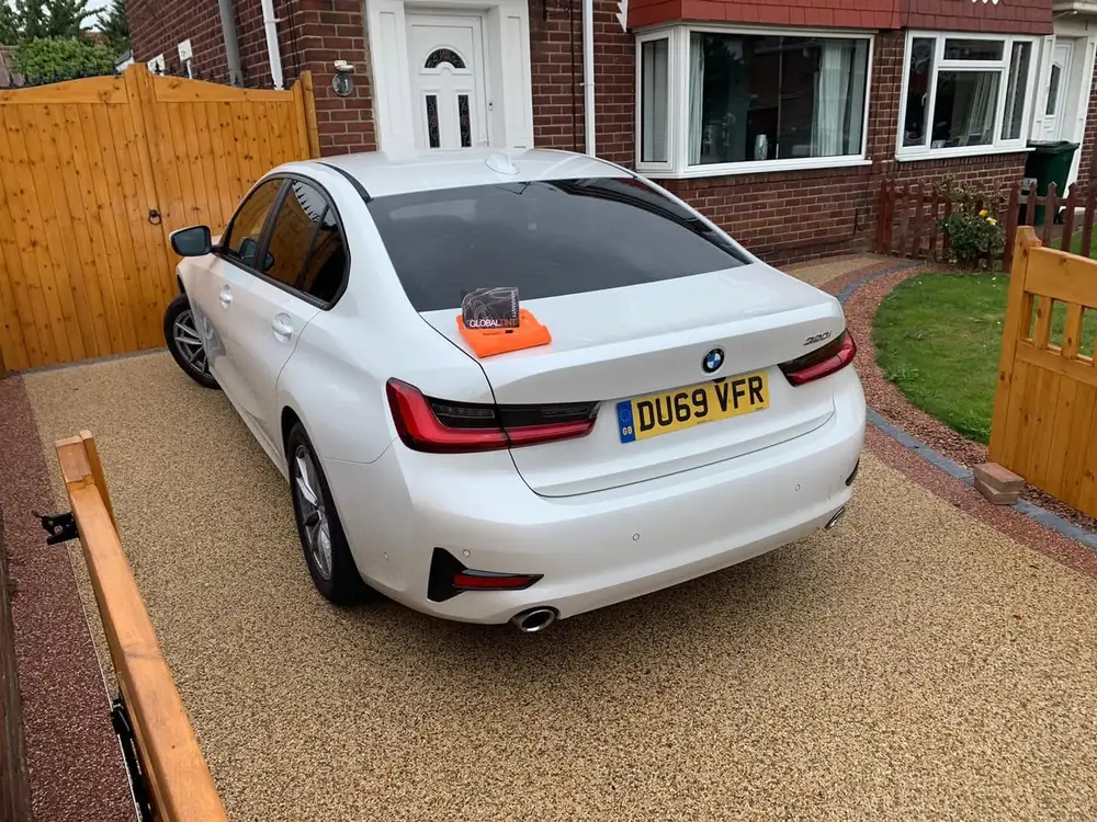 White saloon with dark rear side windows and rear windscreen, parked on a driveway