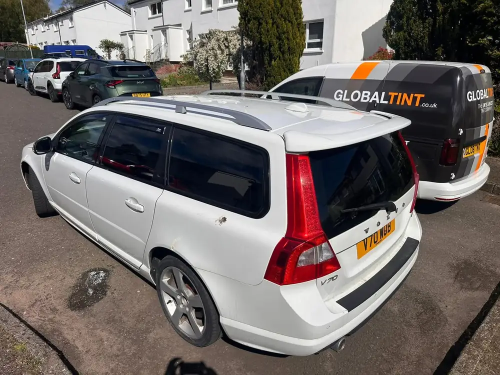 White Volvo V70 estate with dark rear windows and rear windscreen, parked beside a Global Tint van