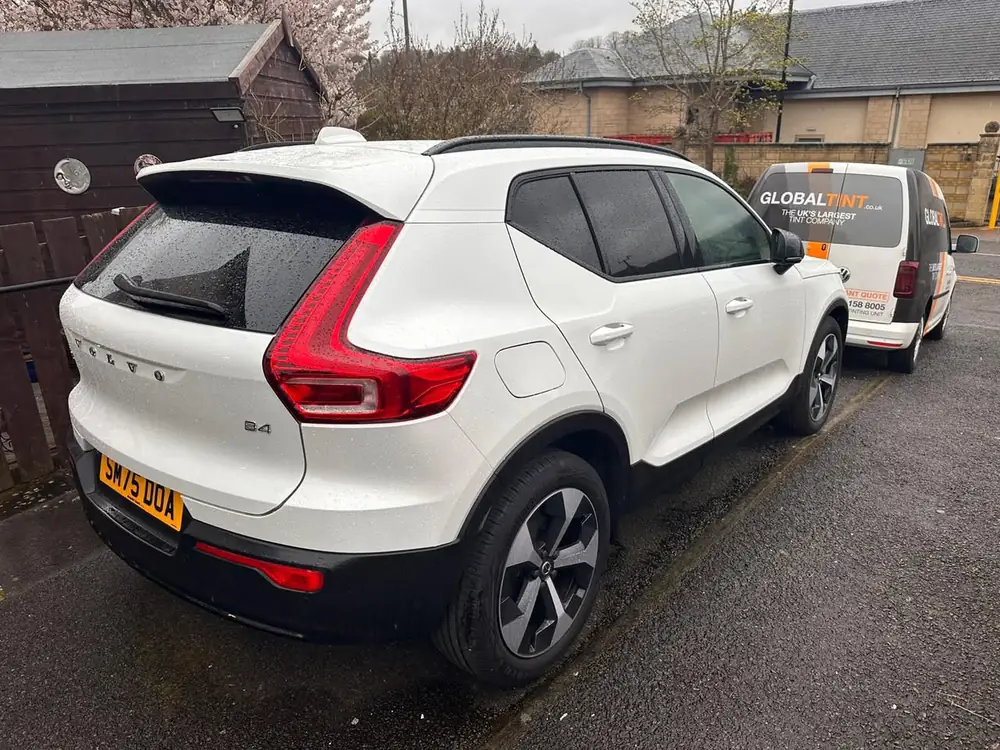 White Volvo XC40 with dark rear side windows and back windscreen, parked behind a Global Tint van.