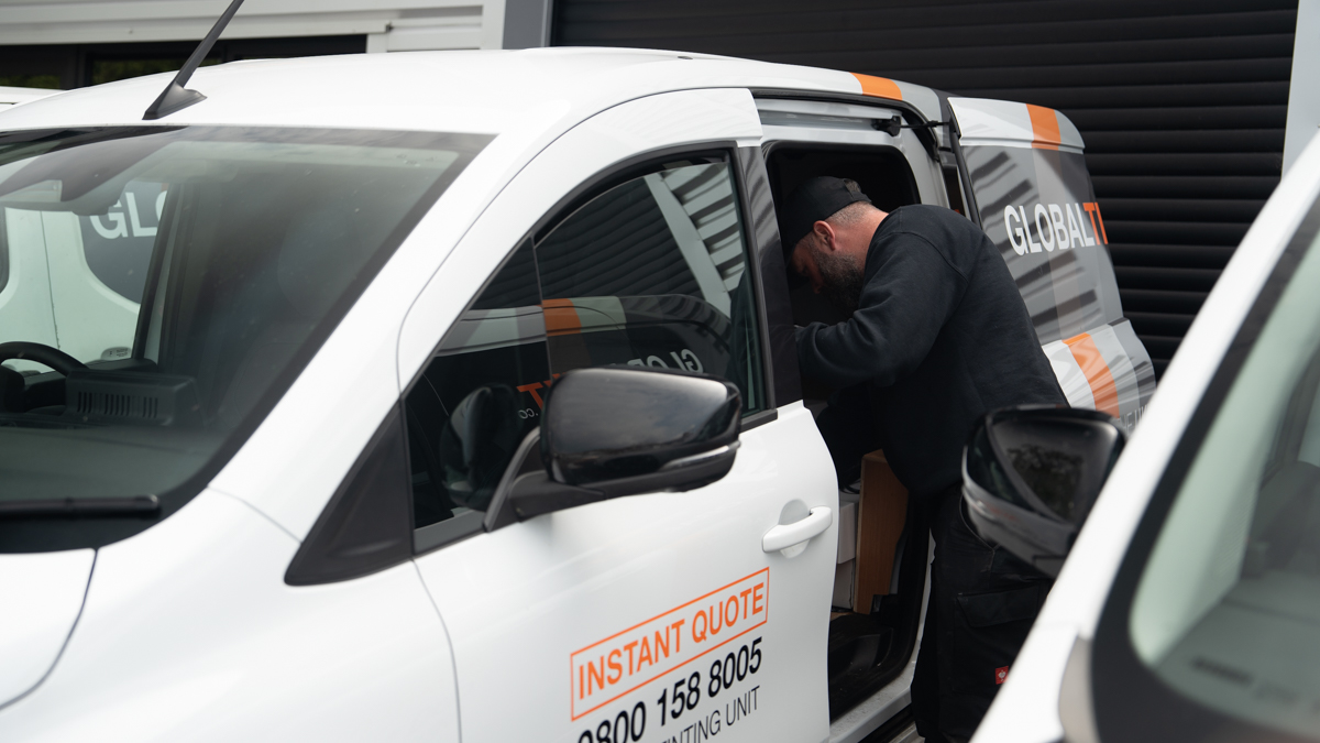A Global Tint installer at work in the door of the mobile tinting van